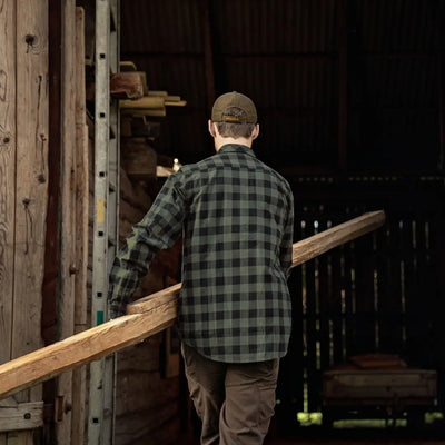 Person in a plaid shirt carrying a wooden board with Harkila Scandinavian Long Sleeve Shirt