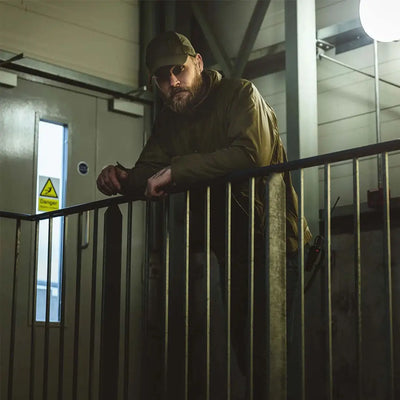 Bearded man in cap wearing Highlander Halo Smock, leaning on a railing