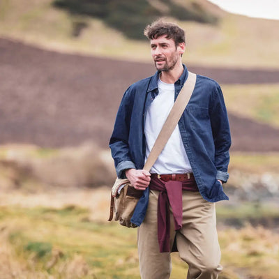 Man in a blue jacket and khaki pants with a messenger bag, showing Fife Archerfield long sleeved denim shirt