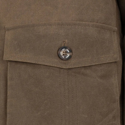 Close-up of a brown Balerno waxed canvas barn coat pocket with a button