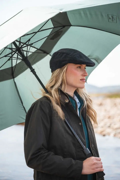 Black waterproof Hoggs of Fife Caledonia wax jacket with flat cap and striped umbrella