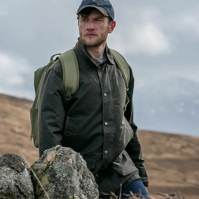 Man in Hoggs of Fife Caledonia Men’s Wax Jacket exploring rugged landscape with water resistant qualities