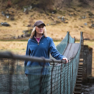 Woman in blue fleece on a suspension bridge wearing a stylish Hoggs of Fife zip fleece