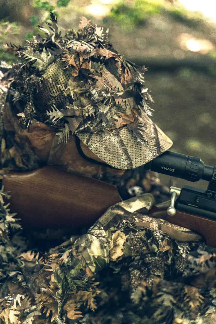 Camouflaged hunter wearing a rifle with a Jack Pyke LLCS 3D Baseball Cap