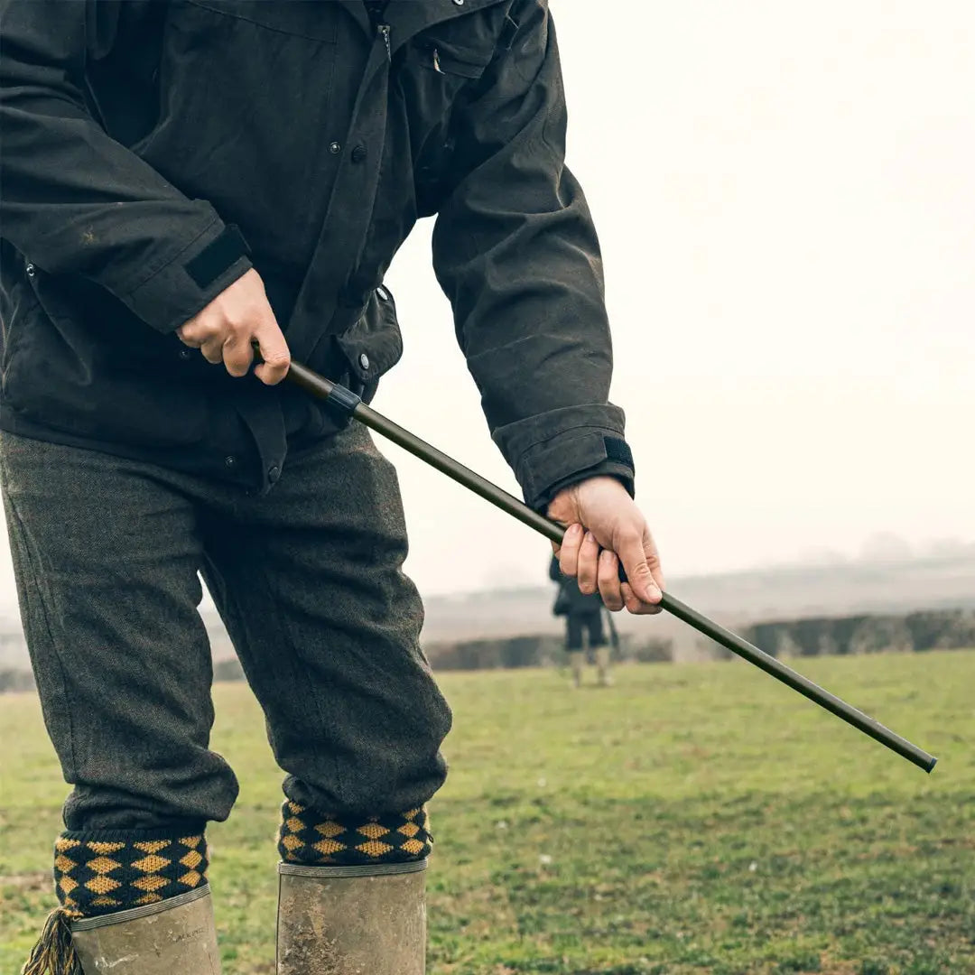 Person in boots with a walking stick using the Jack Pyke Magnetic Cartridge Collector