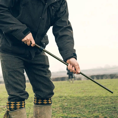 Person in boots with a walking stick using the Jack Pyke Magnetic Cartridge Collector