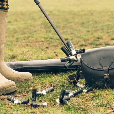 Shotgun and shells on grass near Jack Pyke Magnetic Cartridge Collector bag