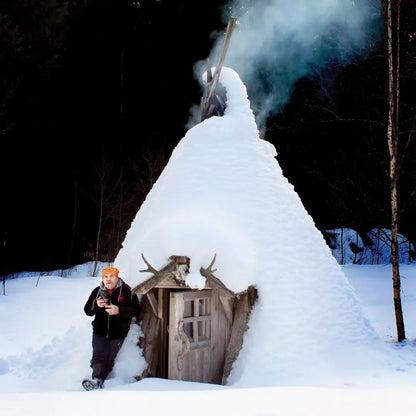 Snow-covered wooden hut with smoking chimney, perfect for country clothing and outdoors vibes