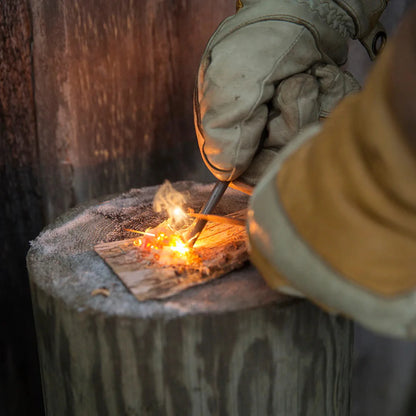 Gloved hand using Kupilka Firesteel to create sparks with a compact striker