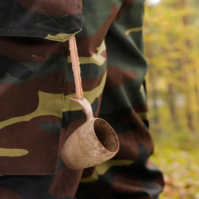 Wooden shot cup dangling from camouflage pants, perfect for country clothing and hunting