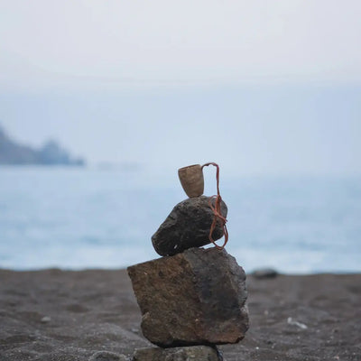 Stacked beach rocks with a Kupilka Shot Cup, perfect for country clothing lovers