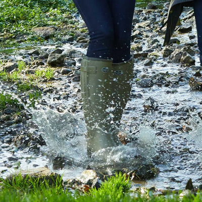 Green rubber boot splashing in mud, showcasing Le Chameau Women’s Neoprene Lined Wellington Boots
