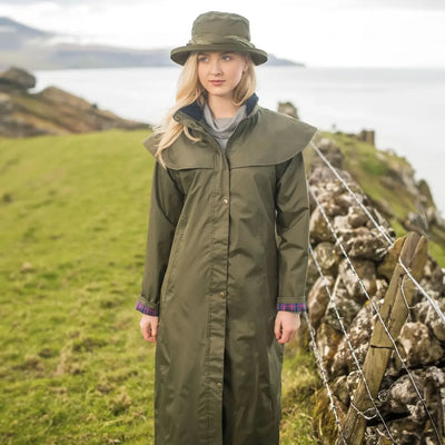 Woman in a long olive green raincoat and wide-brimmed hat with Lighthouse Canterbury Waterproof style