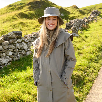 Woman in a gray raincoat and wide-brimmed hat featuring the Lighthouse Canterbury Waterproof