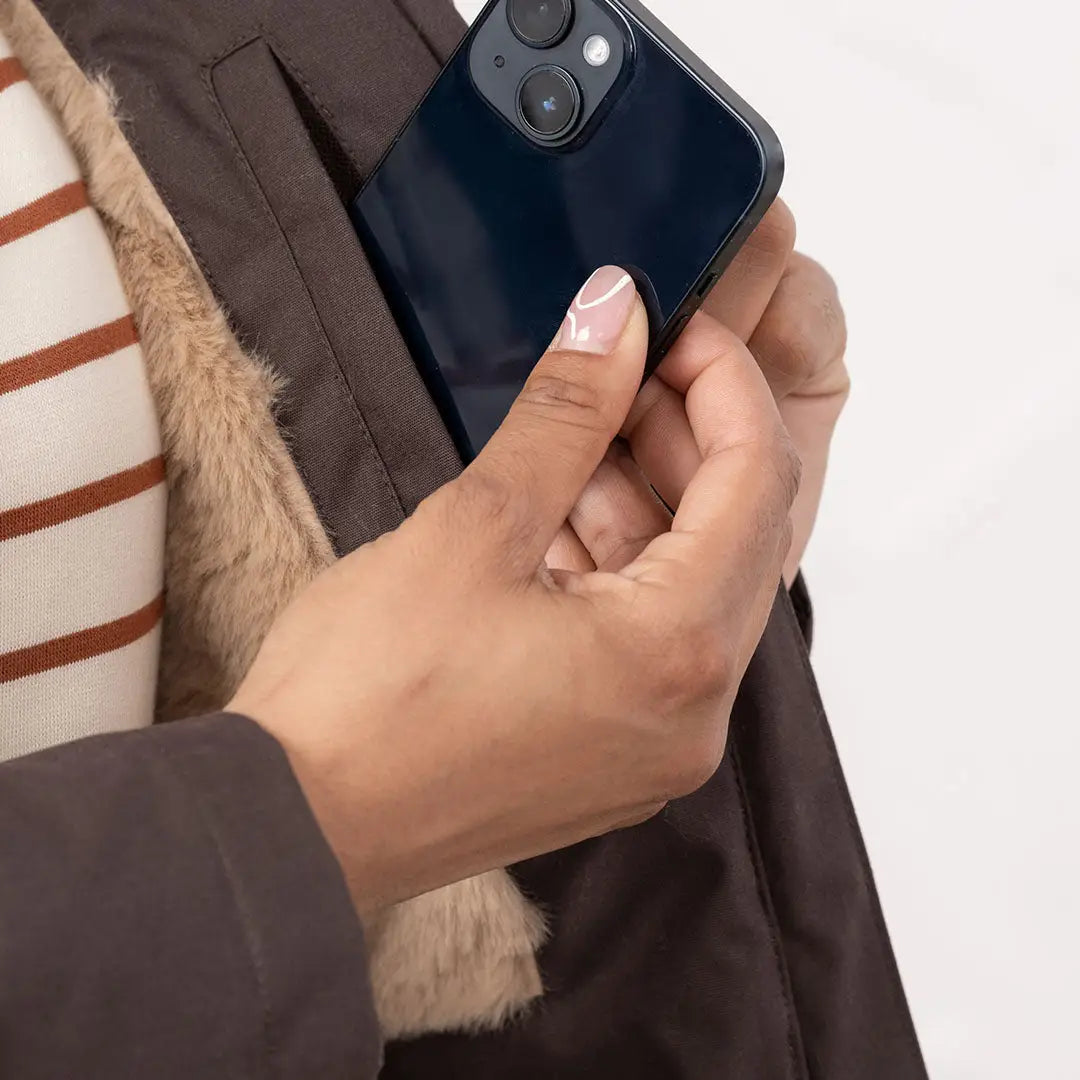 Hand placing smartphone in lighthouse isobel coat pocket with faux fur lining