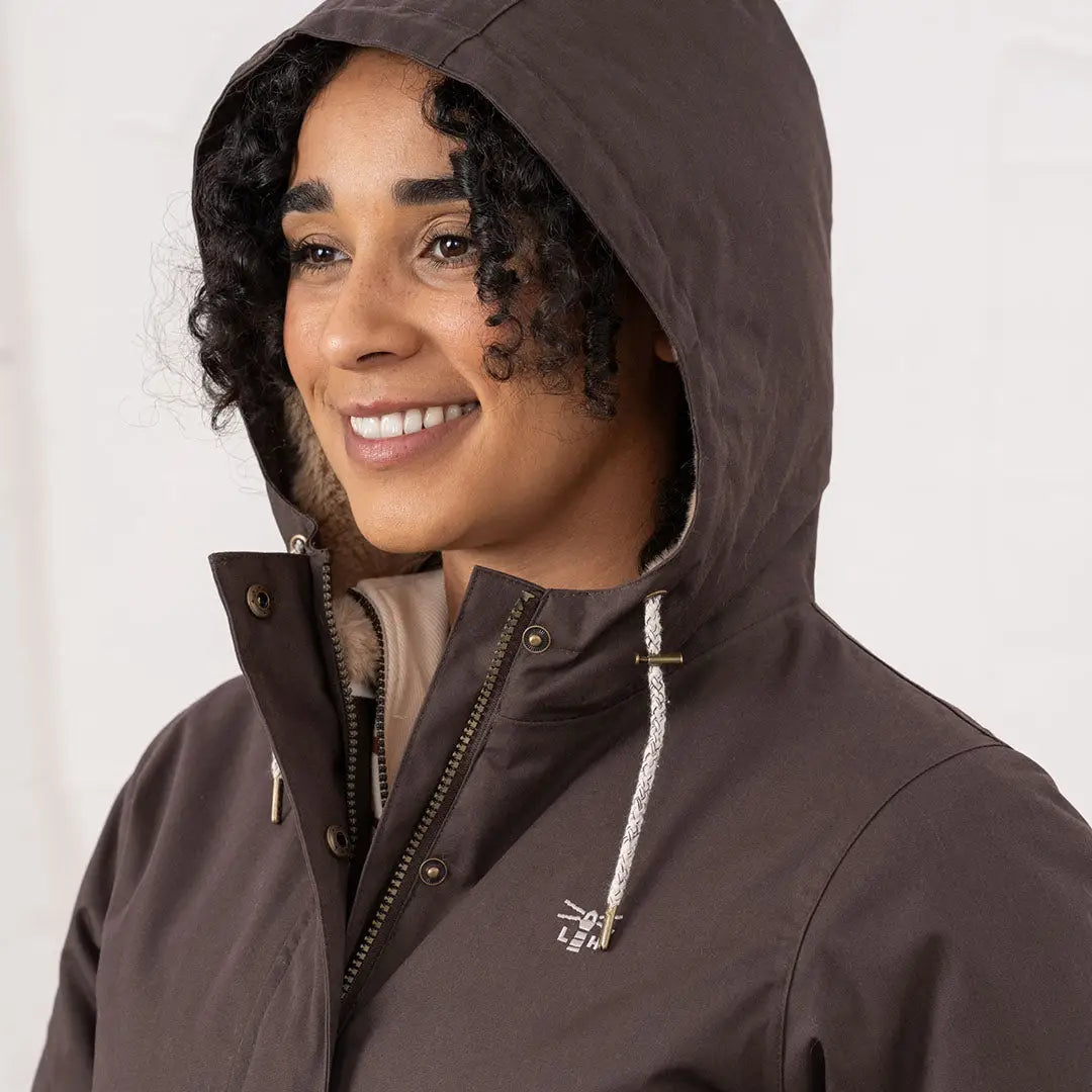 Woman wearing a Lighthouse Isobel Coat dark brown hooded jacket with light lining