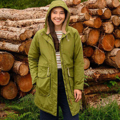 Smiling woman in green Lighthouse Isobel Coat with striped shirt and dark pants