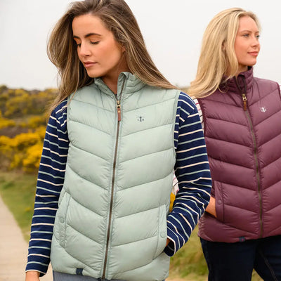 Two women modeling Lighthouse Laurel Ladies quilted puffer vests in green and burgundy