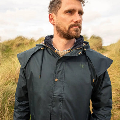 Man in a dark green Lighthouse Stockman full length waterproof rain coat with a hood