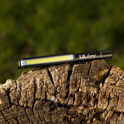 Handheld NEBO Lil Larry work light on weathered wood, perfect for inspections and repairs