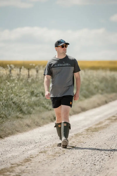 Man in boots walking on dirt road wearing New Forest 2-Tone Graphic T-Shirt in forest clothing graphic