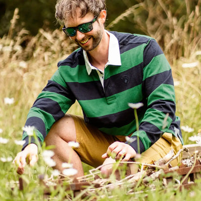 Man in a green and navy striped rugby shirt enjoying the outdoors in a field