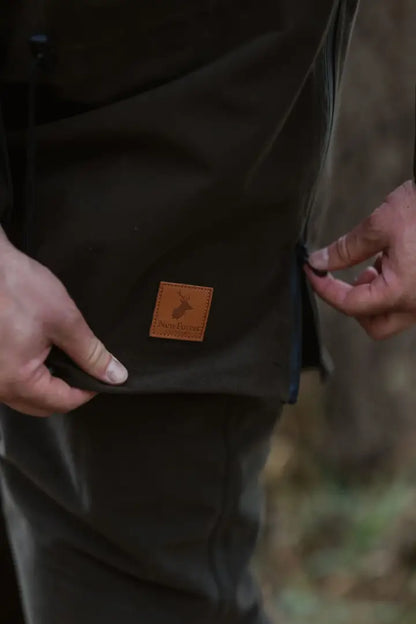 Hands adjusting dark forest country sport smock with brown patch and side zipper