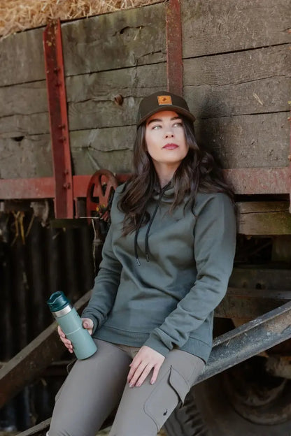 Woman in green hoodie wearing the New Forest Country Sport Trucker Hat, iconic trucker hat style