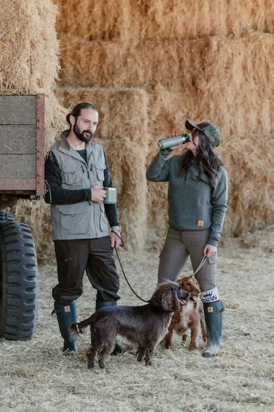 Couple with dogs in barn wearing New Forest Explorer Gilet for forest adventures