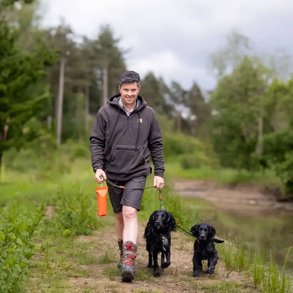 Man walking two black dogs in forest heathland wearing the New Forest Heathland Hoodie