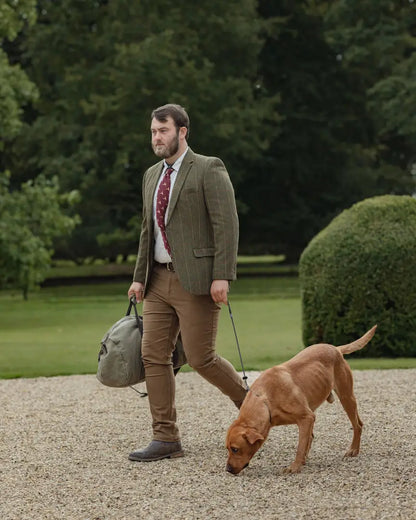 Man in Forest Heritage Tweed Blazer walking a brown dog on a leash outdoors