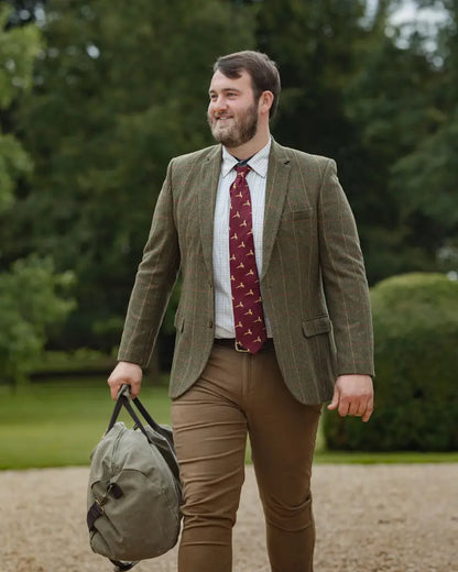 Man in forest heritage tweed blazer with plaid shirt and duffel bag, stylish look