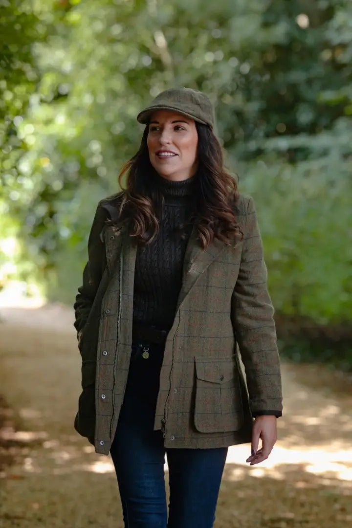 Super stylish ladies field coat: woman in green tweed jacket and flat cap outdoors