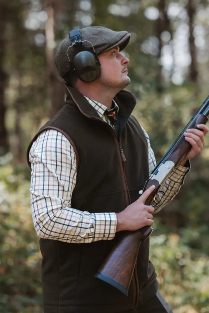 Man in hunting attire with shotgun wearing forest knightwood fleece gilet and ear protection