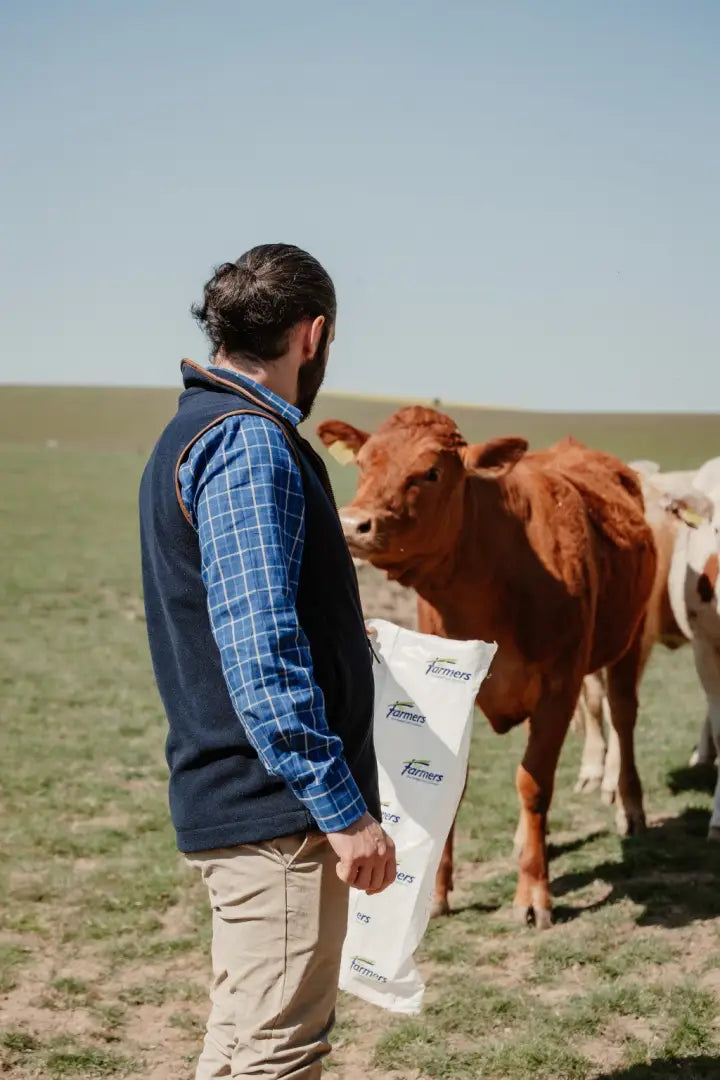 Farmer with feed bag near cattle wearing Forest Knightwood knightwood fleece gilet