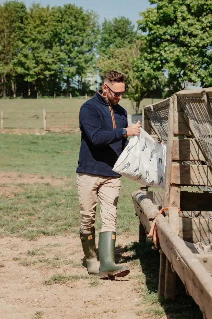 Man feeding livestock in New Forest Knightwood Quarter Zip Fleece, perfect quarter zip fleece wear