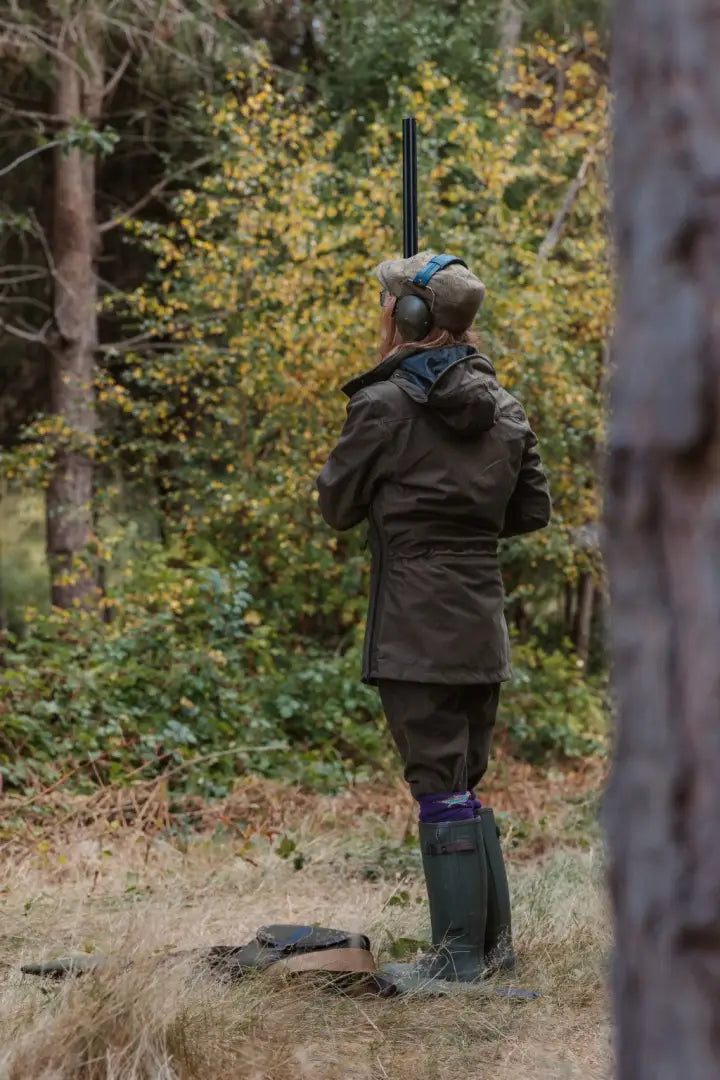 A person in hunting gear with ear protection holding a shotgun in New Forest Ladies Country Sport Smock