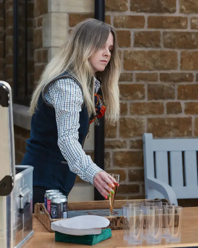Woman with long blonde hair in forest ladies fleece gilet holding champagne glass