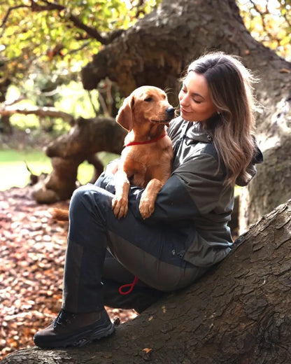 Woman holding a light brown dog wearing a red collar wearing New Forest Ladies Nightjar Trousers