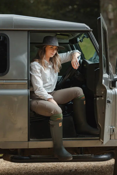 Forest ladies outdoor style with ladies outdoor stretch trousers, woman in plaid shirt in Land Rover