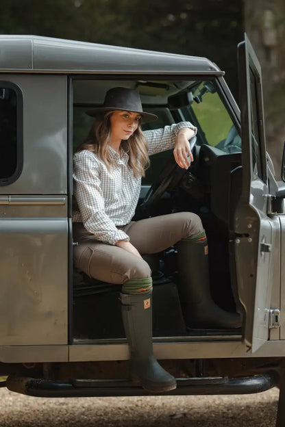 Forest ladies outdoor style with ladies outdoor stretch trousers, woman in plaid shirt in Land Rover