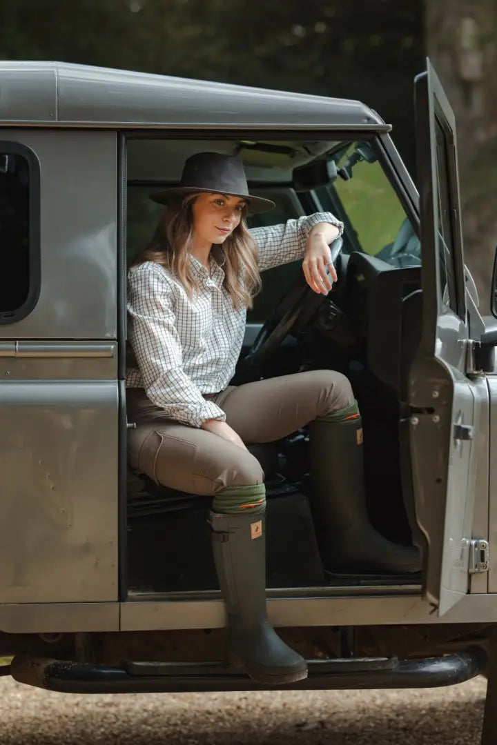 Woman in plaid shirt and wellington boots sitting in Land Rover with New Forest Tattersall Shirt