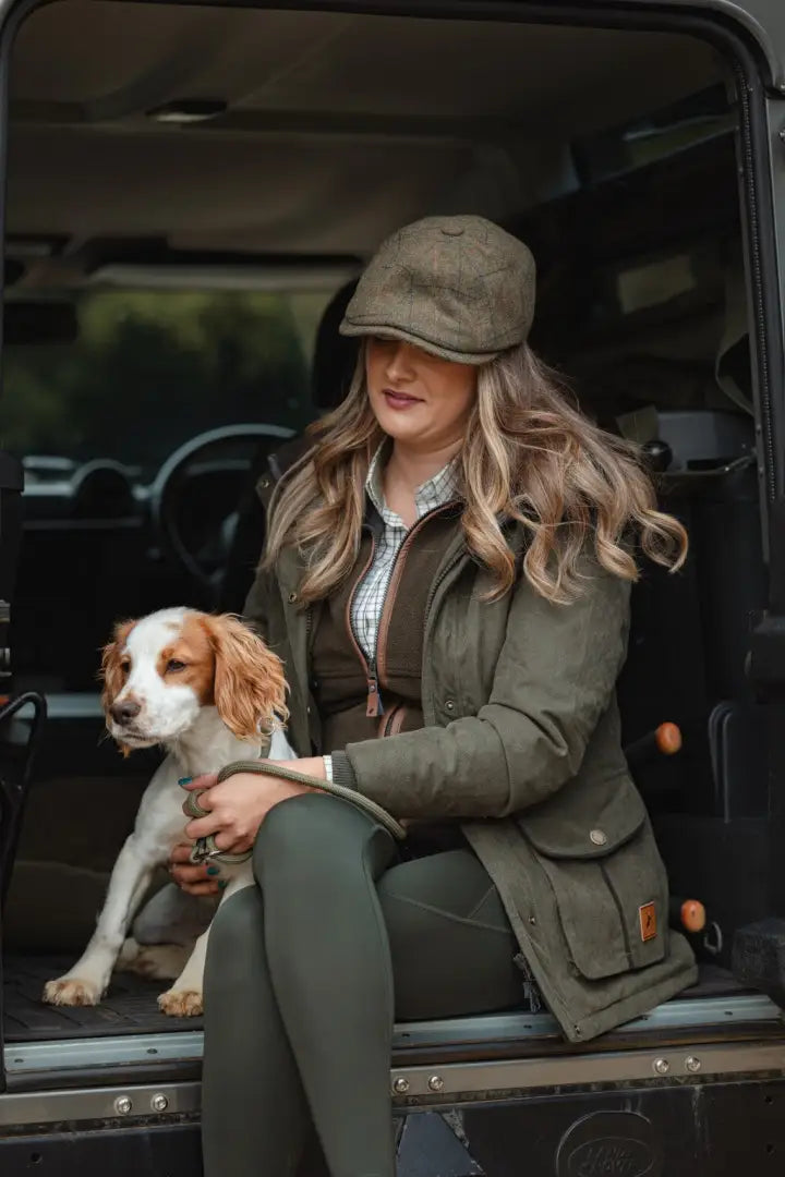 Woman in a green forest ladies robyn jacket with dog sitting outdoors