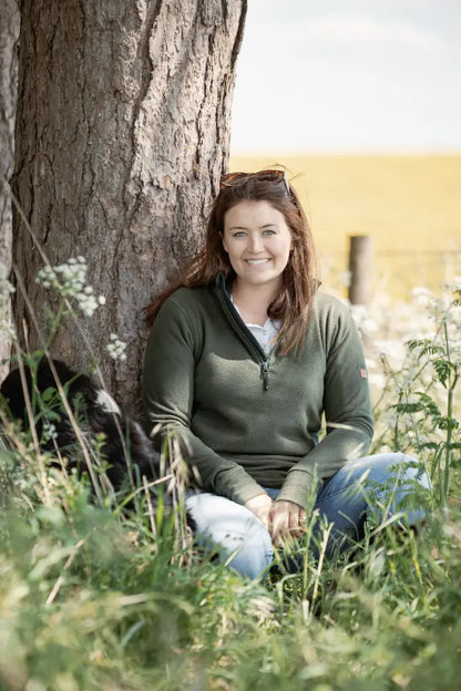 Woman sitting by a tree wearing New Forest Ladies Trail Fleece on forest trail