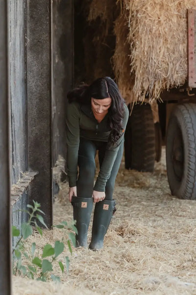 Woman adjusting green rubber boots in New Forest Ladies Trail Fleece for forest trail walks