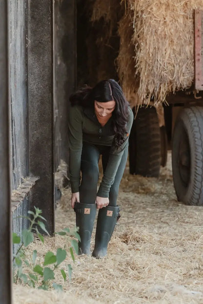 Woman adjusting green rubber boots in New Forest Ladies Trail Fleece for forest trail walks