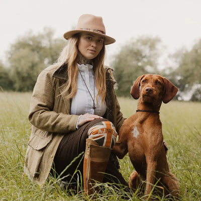 Woman in a fantastic quality ladies tweed jacket sitting with a Vizsla in a grassy field