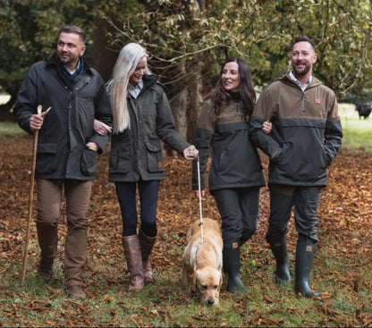 Group walking outdoors in matching forest moleskin jeans and boots with a dog