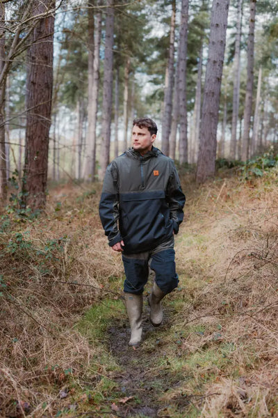 Man in outdoor clothing wearing a Forest Nightjar Smock while walking through woods