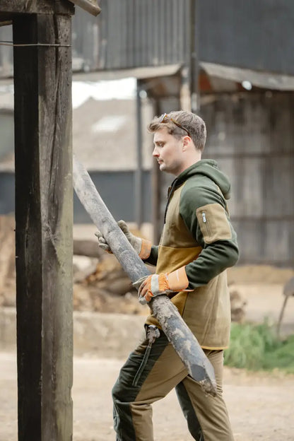 Man carrying wooden stakes in forest nightjar trousers, perfect for outdoor adventures